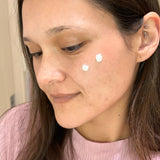 Woman using PDRN Collagen Cream on her face, wearing a pink sweater.
