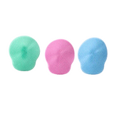 Three silicone face scrubber heads in mint green, pink, and light blue, arranged side by side on a white background.