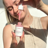 Woman holding a bottle of Lumenshine Peptide Serum with a dropper.