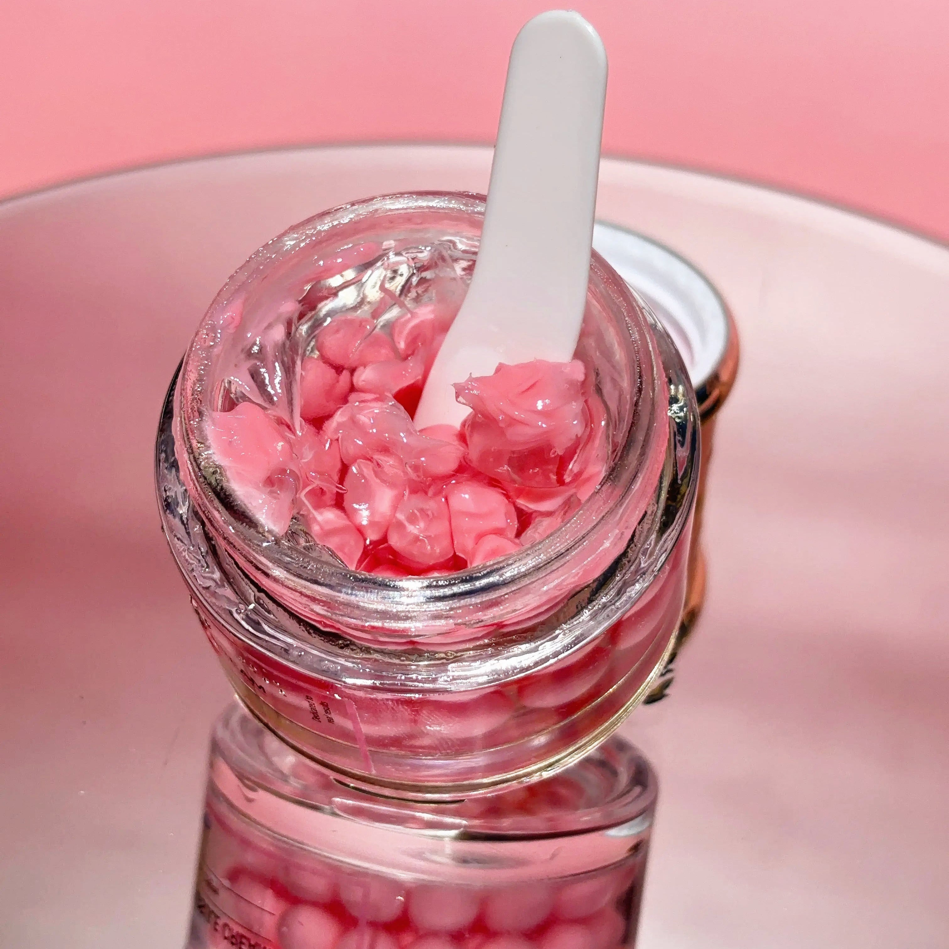 Luminous Empire PDRN Collagen Capsules Jar of pink gel with a white spatula on a pink background