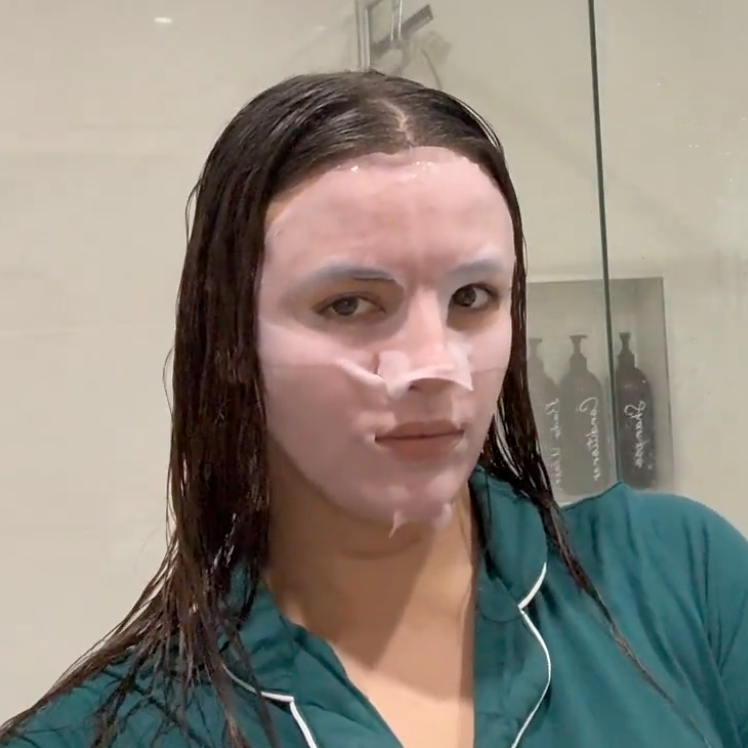 Person applying a face mask in a bathroom
