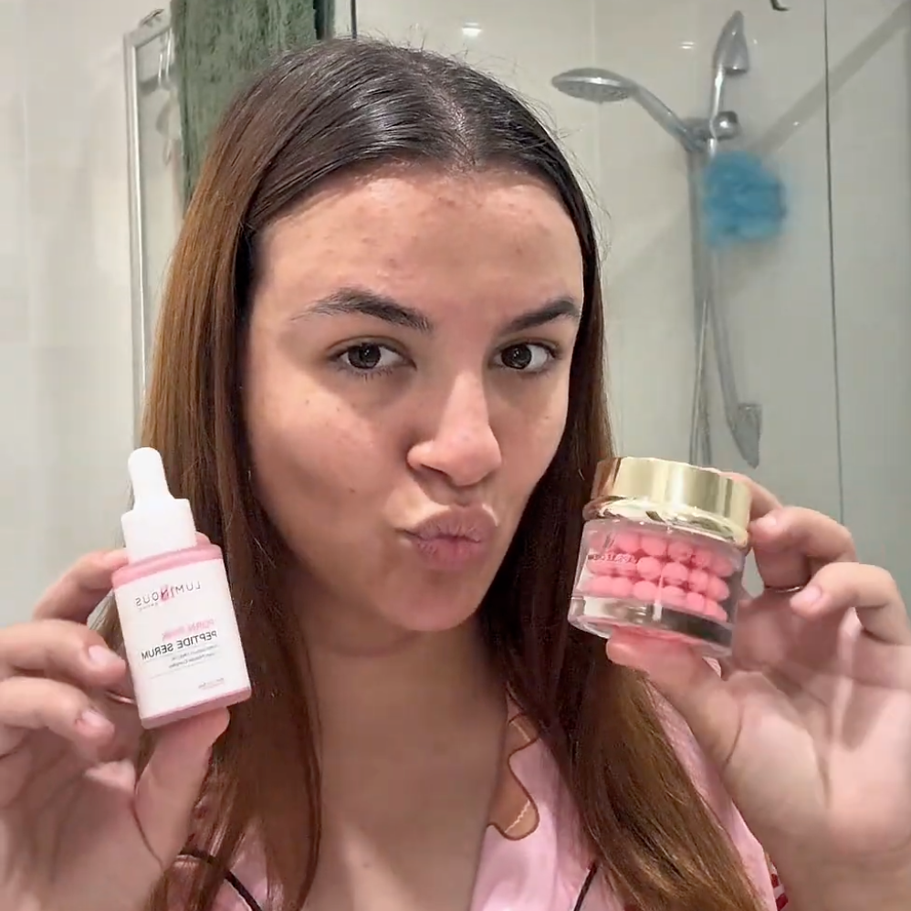 Woman holding Luminous Empire PDRN Serum and PDRN Capsule creams in a bathroom setting