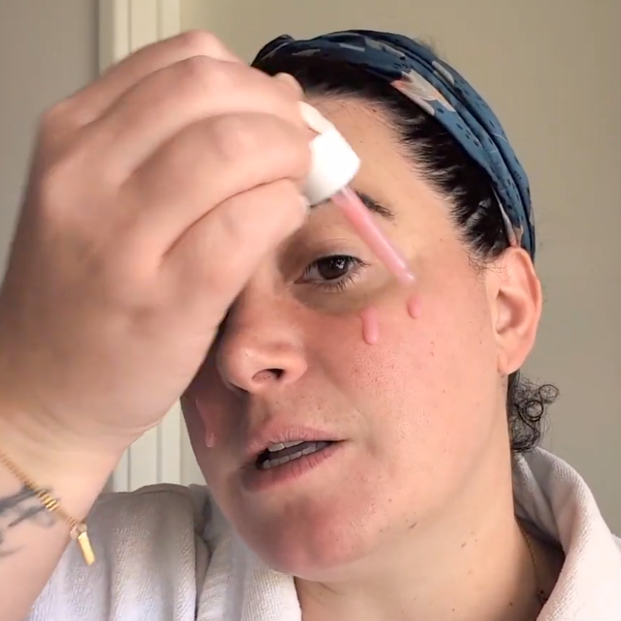 Person applying a product to their face with a dropper.