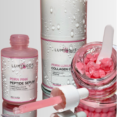 Luminous skincare products including a pink serum, collagen cream, and pink capsules on a reflective surface.