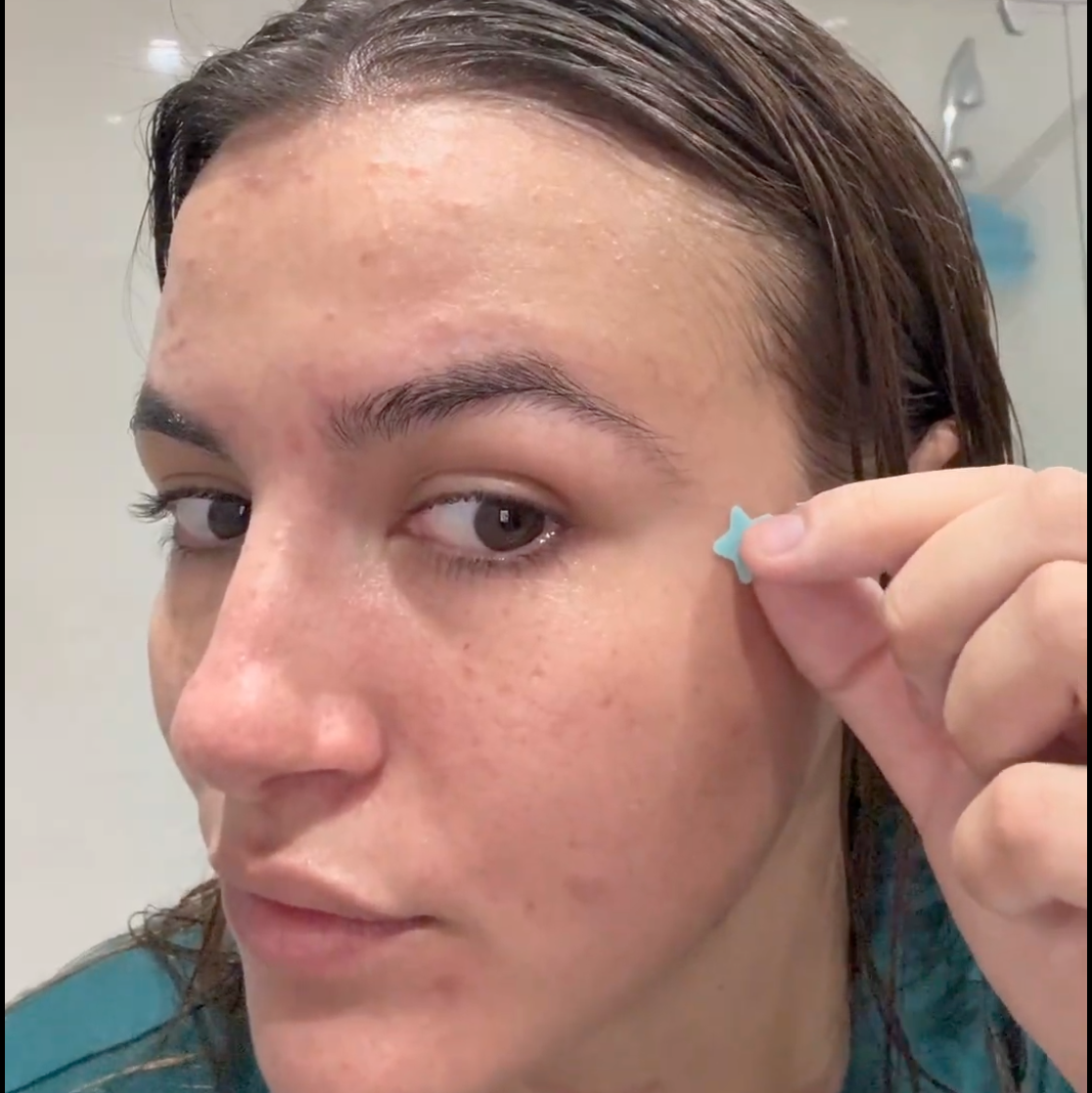 Person applying Acne Rescue Patch to their face in a bathroom setting